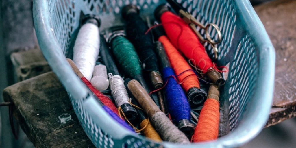 Een mand vol klosjes garen in allerlei kleuren
